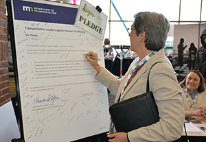 Woman signs a poster-size pledge against human trafficking